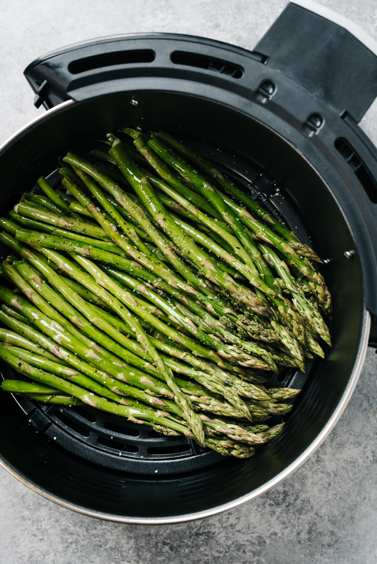 From overheard, asparagus spears tossed with olive oil, salt, and pepper in the basket of an air fryer.