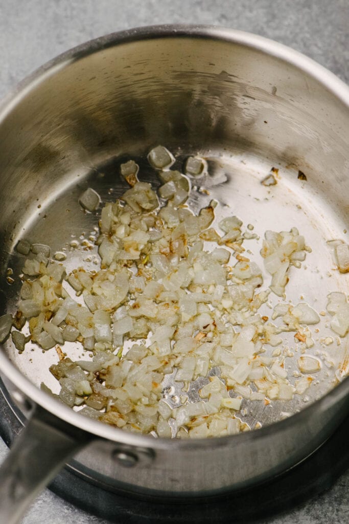 Side view, finely minced onion and garlic sautéed in olive oil until soft in a saucepan.