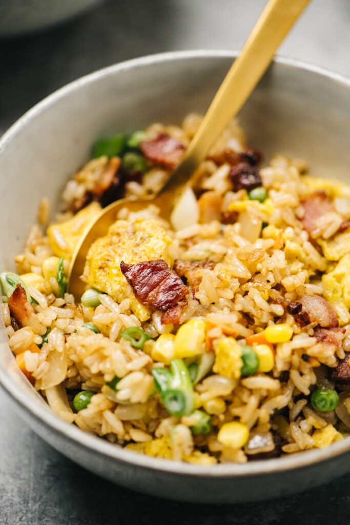 Side view, breakfast fried rice in a bowl with a gold spoon.