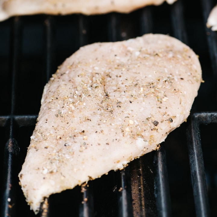 A seasoned chicken breast on a grill.