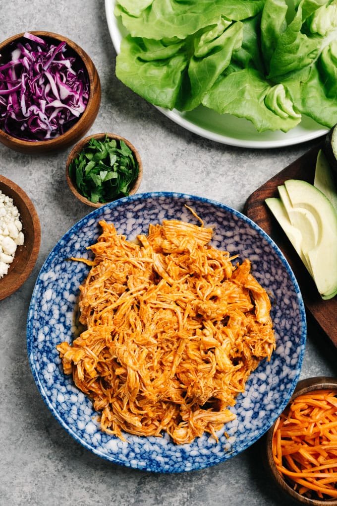 The ingredients for buffalo chicken lettuce wraps arranged on a cement background.