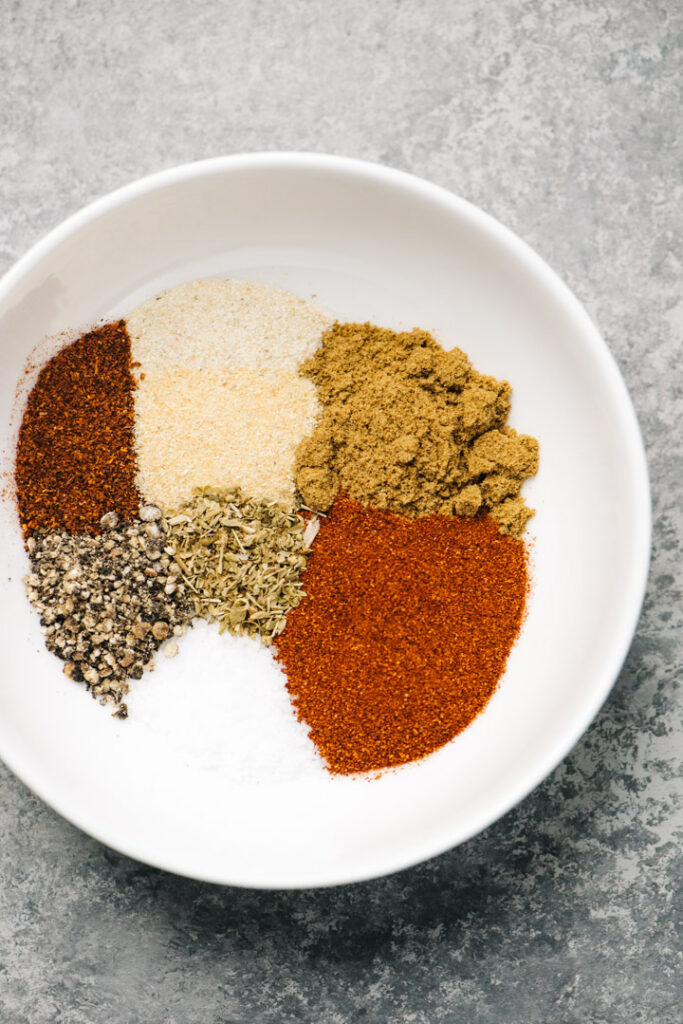 Fajita seasonings ingredients in a small white bowl on a concrete background.