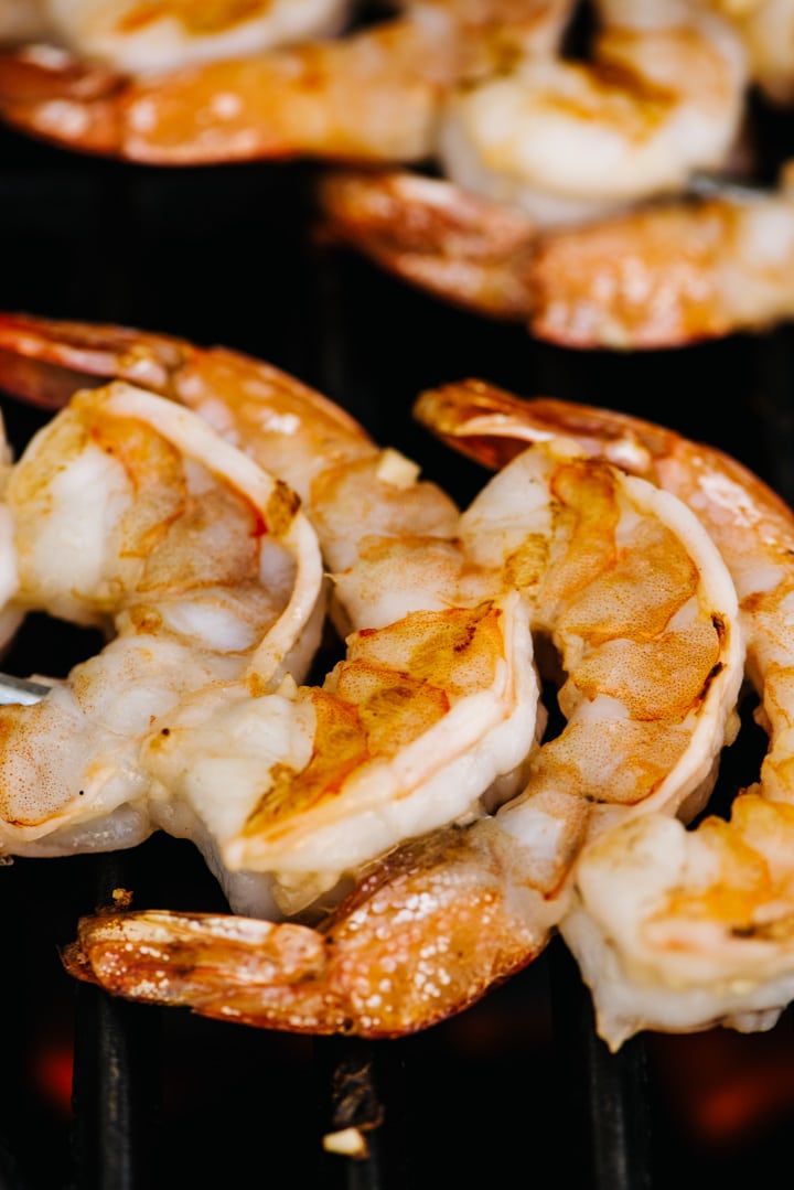 Side view, grilled shrimp on skewers on a gas grill grate.