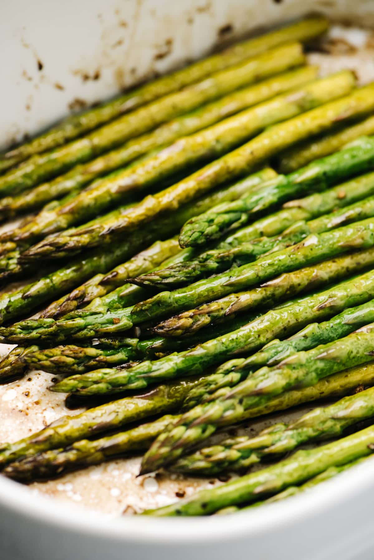 Side view, baked asparagus with balsamic vinegar in a casserole dish.