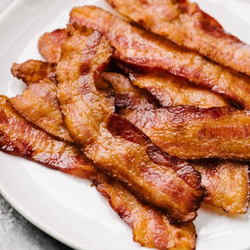 Side view, crispy oven baked bacon on a white plate.