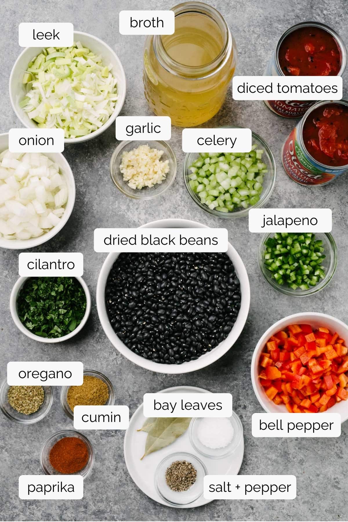 The ingredients for making black bean soup in an Instant Pot in small bowls arranged on a concrete surface. 