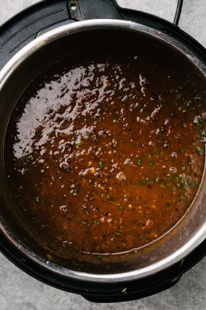 Fresh cilantro stirred into pureed black bean soup in an Instant Pot pressure cooker.