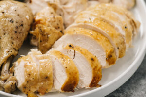 Side view, a carved whole chicken cooked in an instant pot on a white plate.