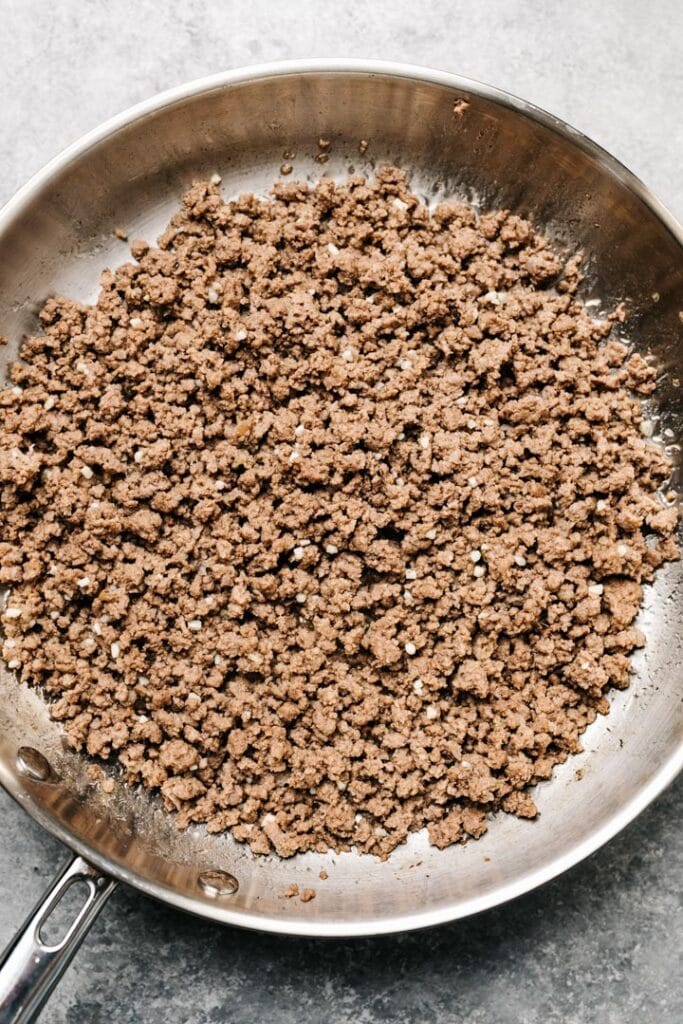 Sauteed ground beef with garlic and ginger in a skillet.