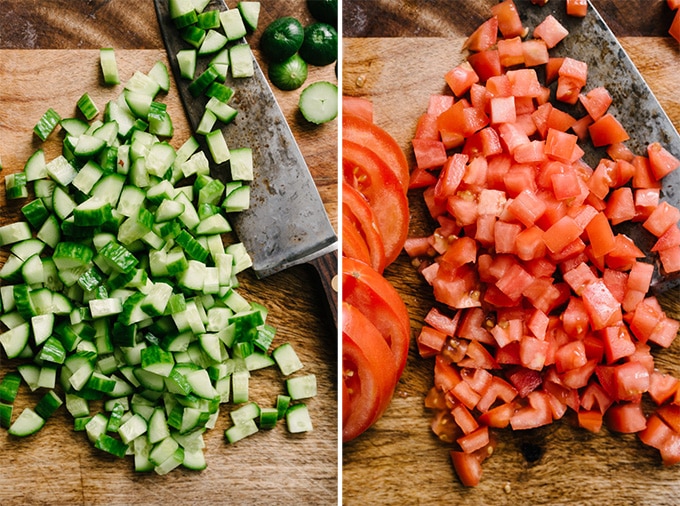 Diced persian cucumbers and diced tomatoes on a cutting board.