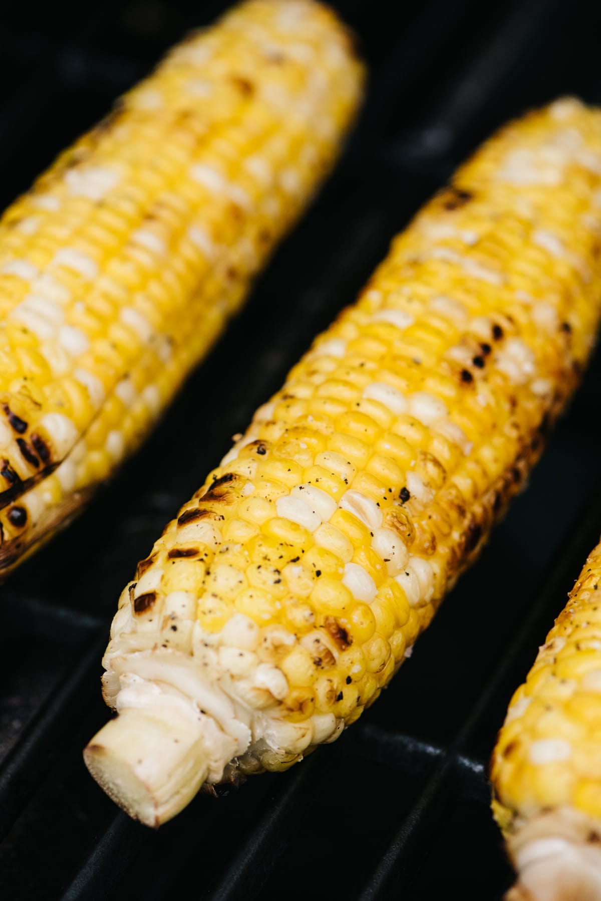 Corn on the cob with husks removed on a gas grill.