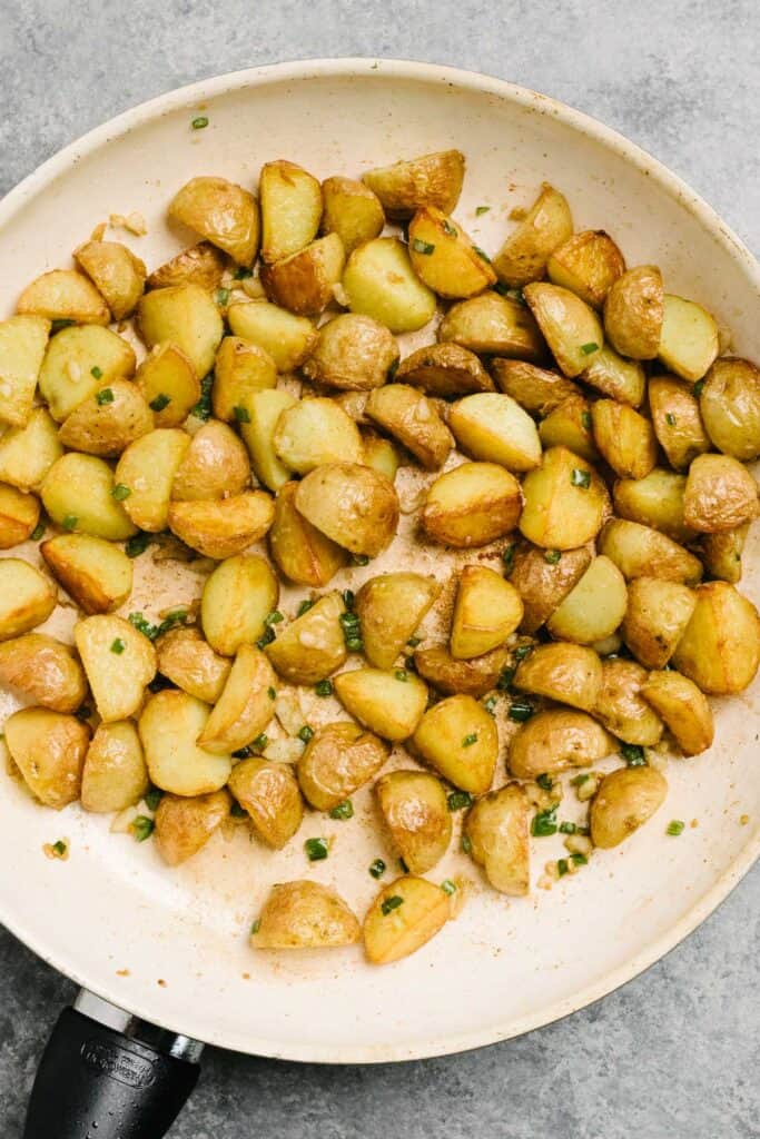 Potato taco filling in a skillet - golden brown gold potatoes with minced serrano chiles, thinly sliced garlic, and cumin.