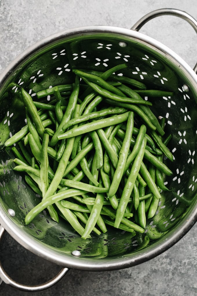 Trimmed and rinsed green beans in a metal colander.