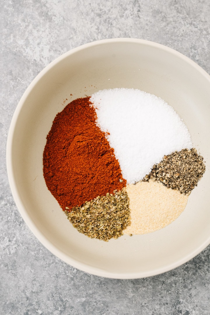 Spices for pulled pork dry rub in a bowl - paprika, salt, pepper, oregano, garlic powder.