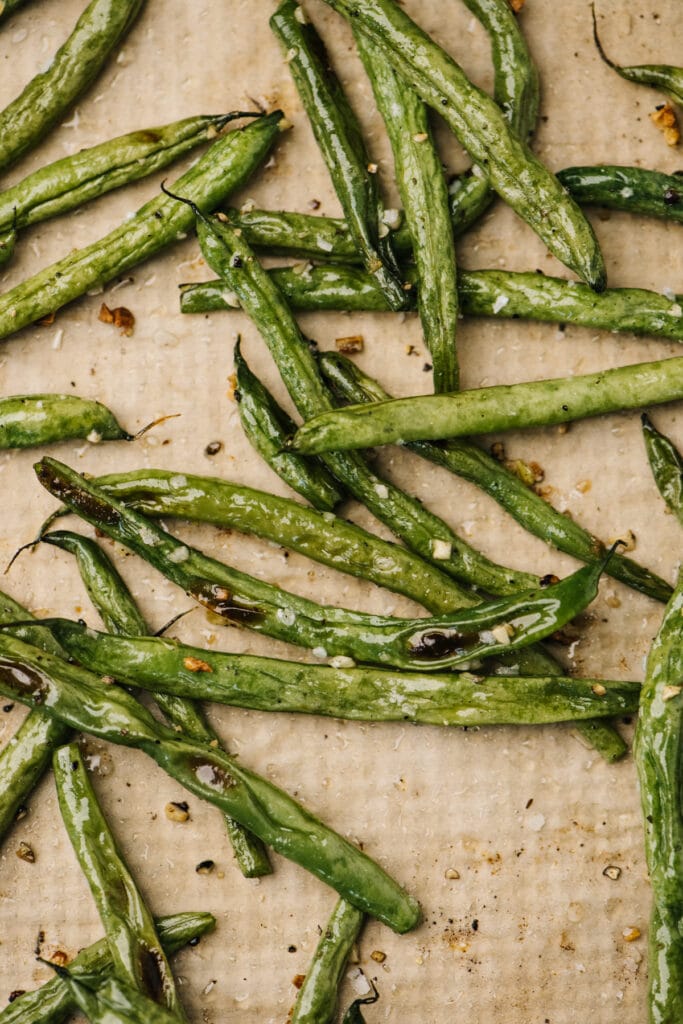 Roasted green beans on a parchment lined baking sheet.