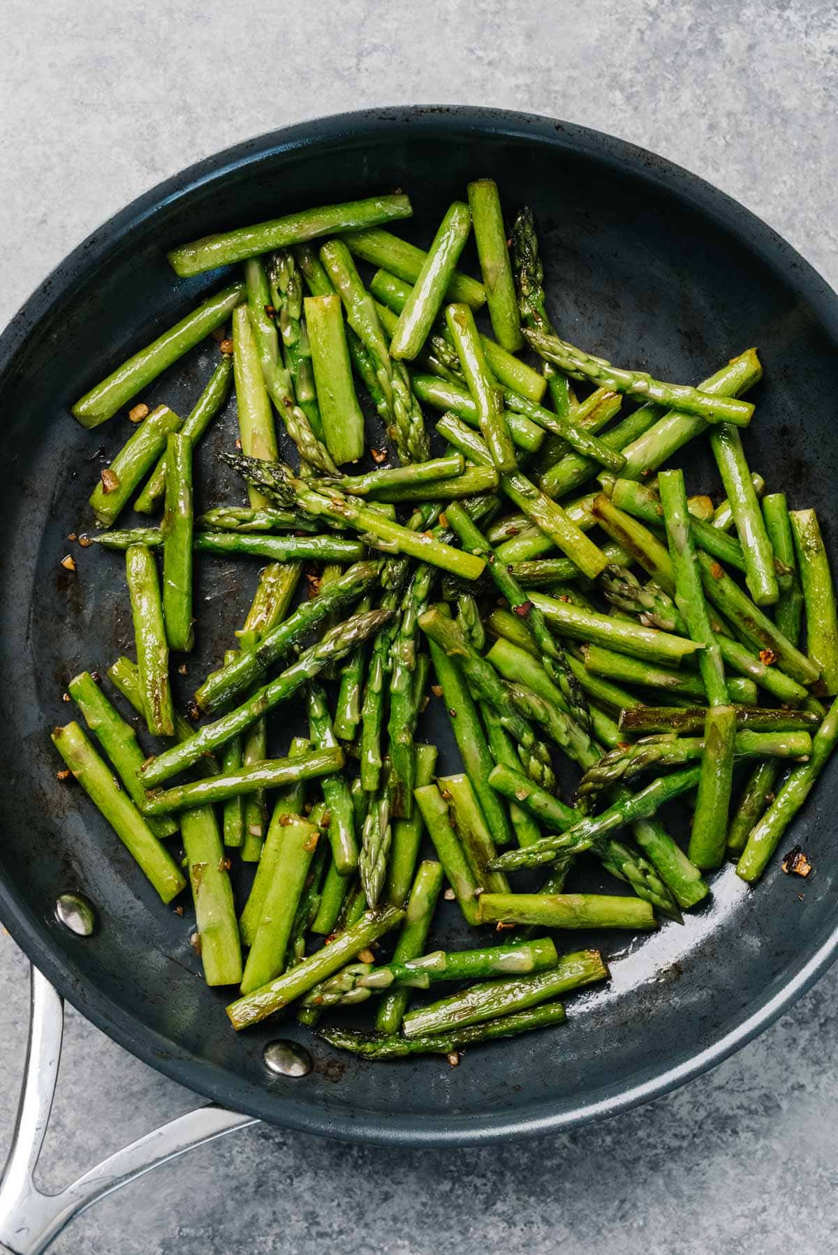 Chopped asparagus sautéing in a skillet.