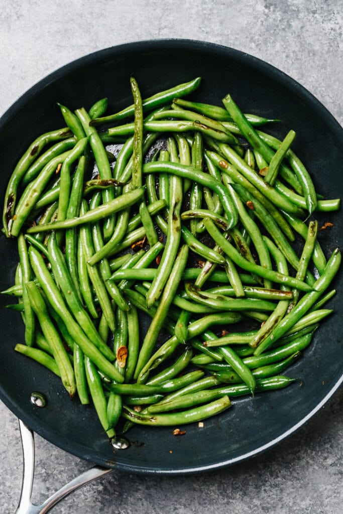 Sautéed green beans with garlic in a skillet.