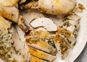 A carved slow cooker chicken on a speckled brown serving plate.