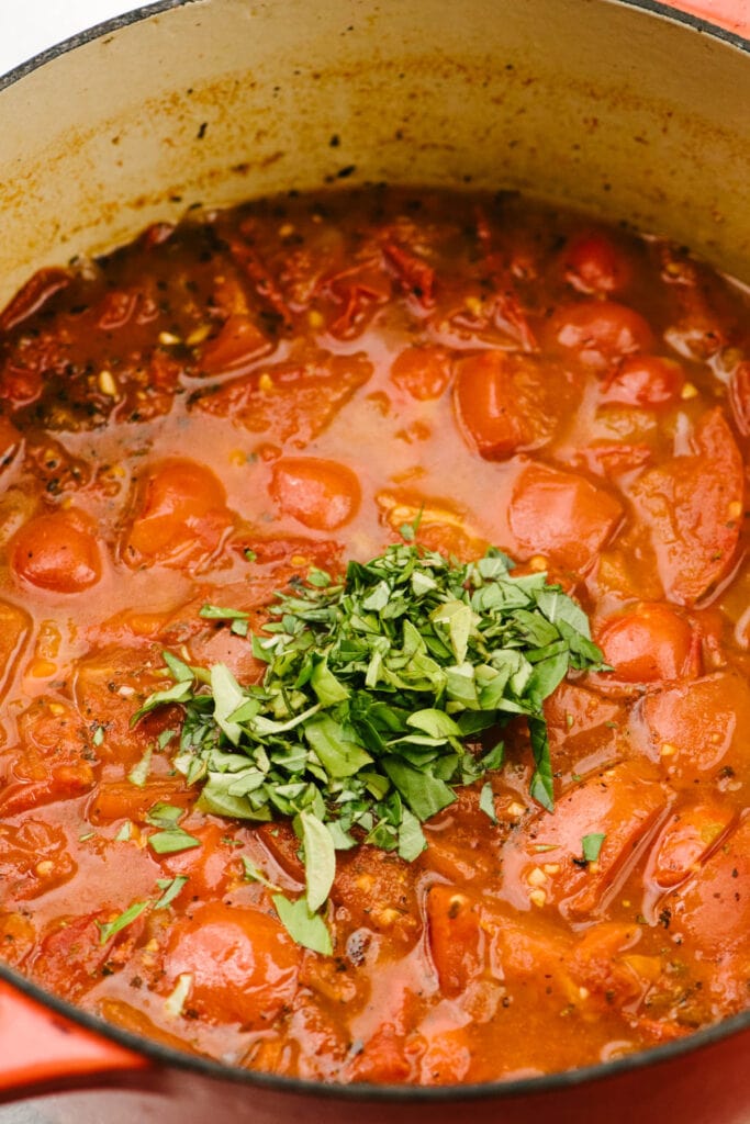 Side view, fresh chopped basil added to tomato basil soup.