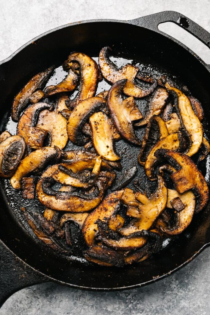 Sauteed portobello mushrooms seasoned with fajita spices in a cast iron skillet.