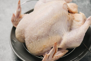 Side view, a dry brined whole chicken on a grey plate.